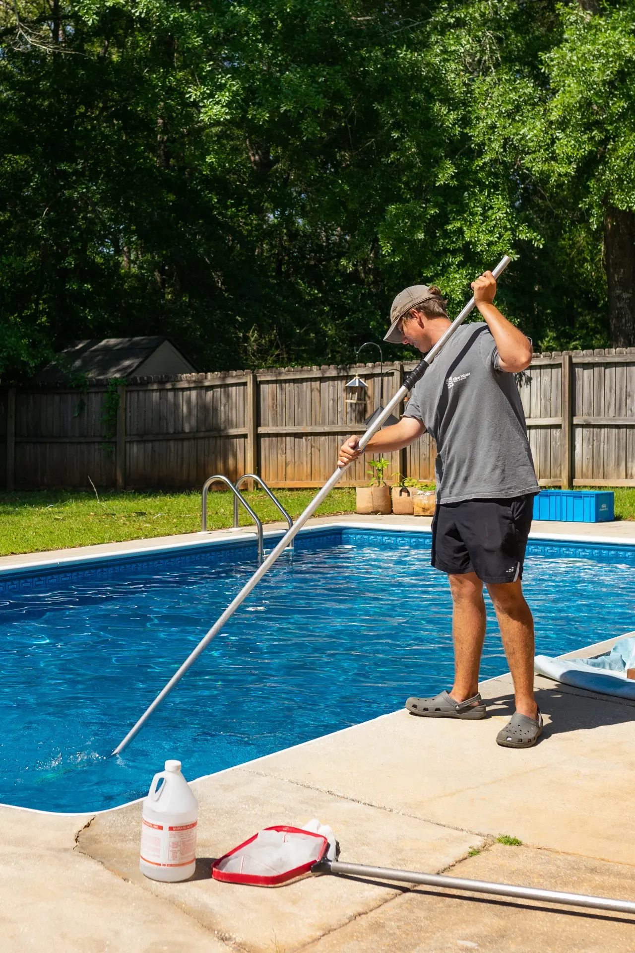 Pool technician brushing a backyard pool